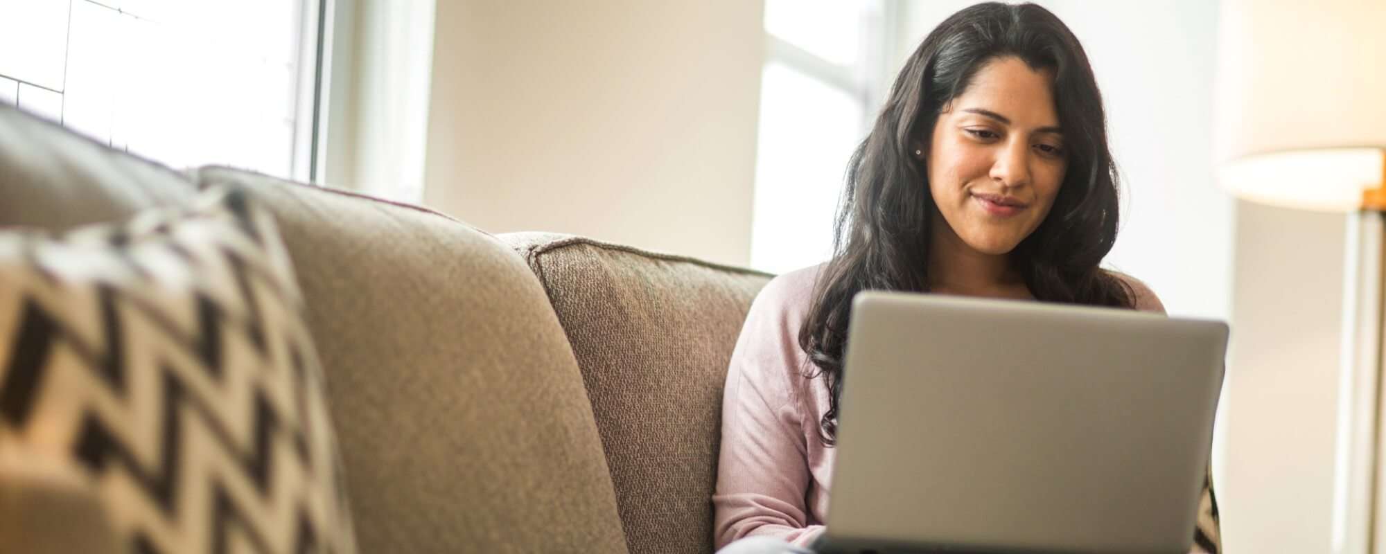 lady looking at her laptop on the couch