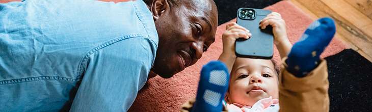 Granddad and baby look at mobile screen