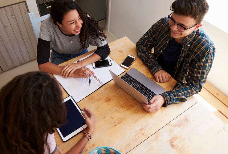 Friends-work-around-a-tabletop-with-multiple-devices