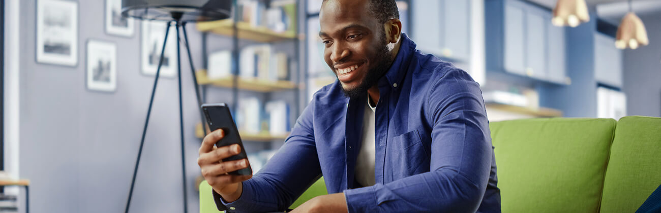 man sitting on a couch scrolling his phone