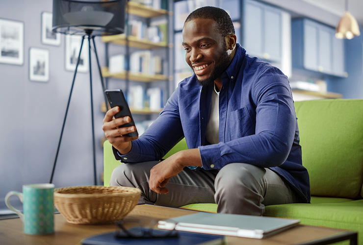 man sitting on a couch scrolling his phone