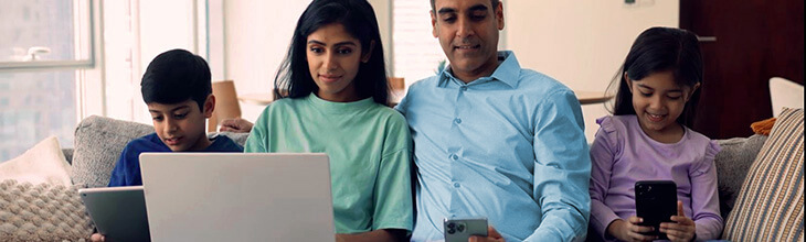 Middle Eastern family sits on sofa streaming on multiple devices