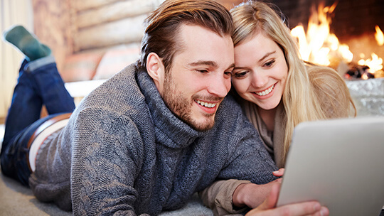 cozy couple watching streaming shows in front of crackling fireplace in the winter